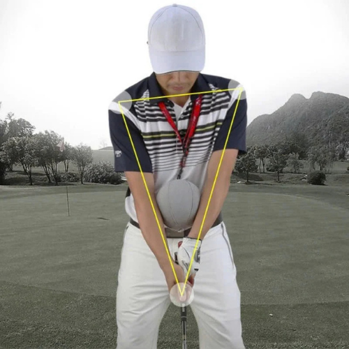 Person on a golf course with a golf club and ball, demonstrating a golf swing technique.
