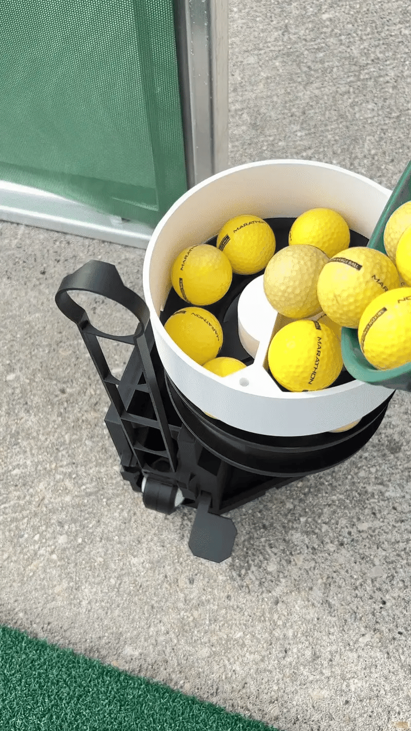 Tennis ball machine with tennis balls on a concrete surface