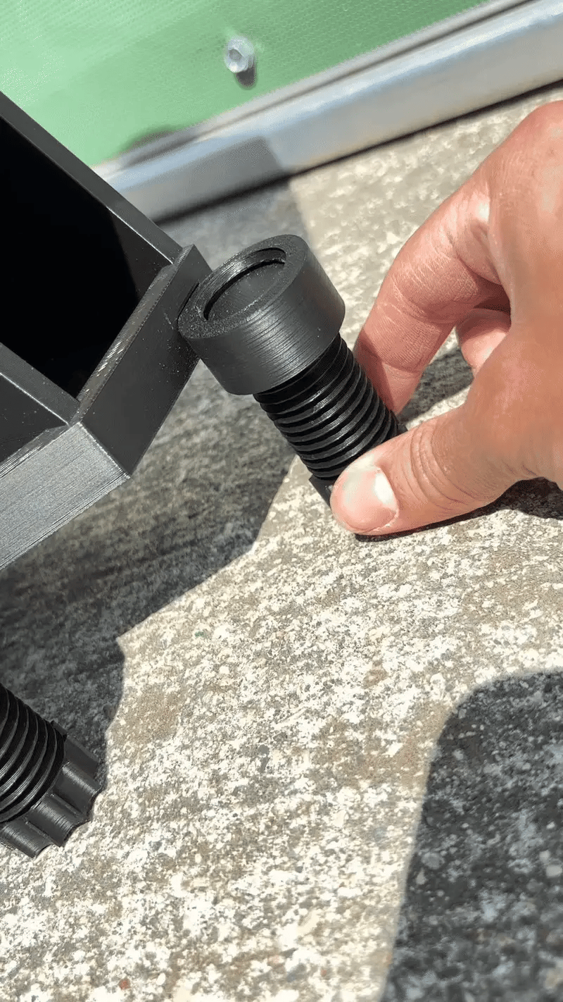 Hand adjusting a black screw on a metal bracket against a concrete surface.
